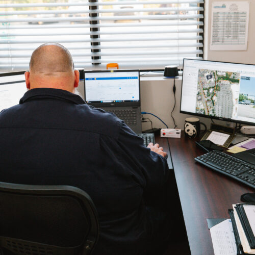 Person at desk with multiple monitors and laptops in office.