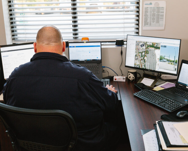 Person at desk with multiple monitors and laptops in office.