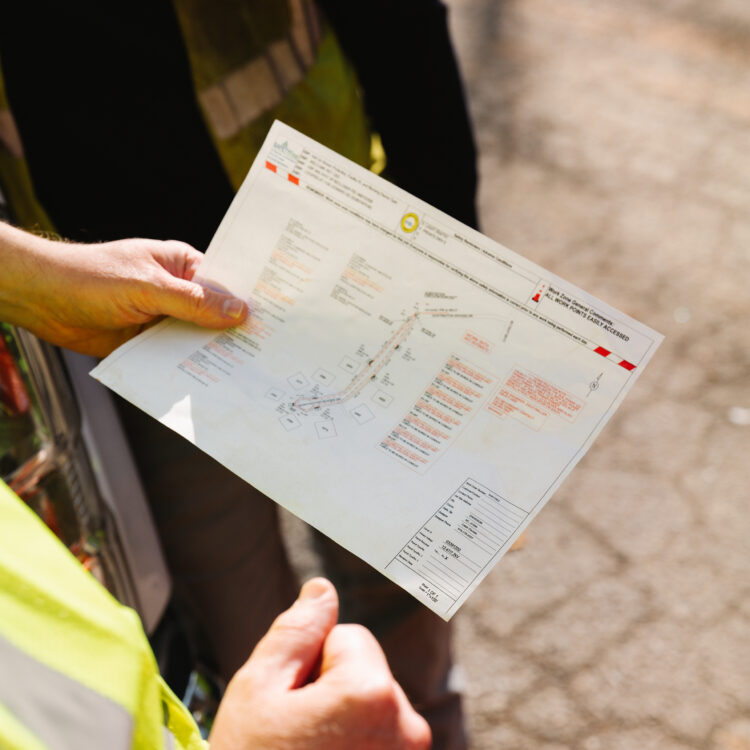 Two people in safety vests review a map outdoors.