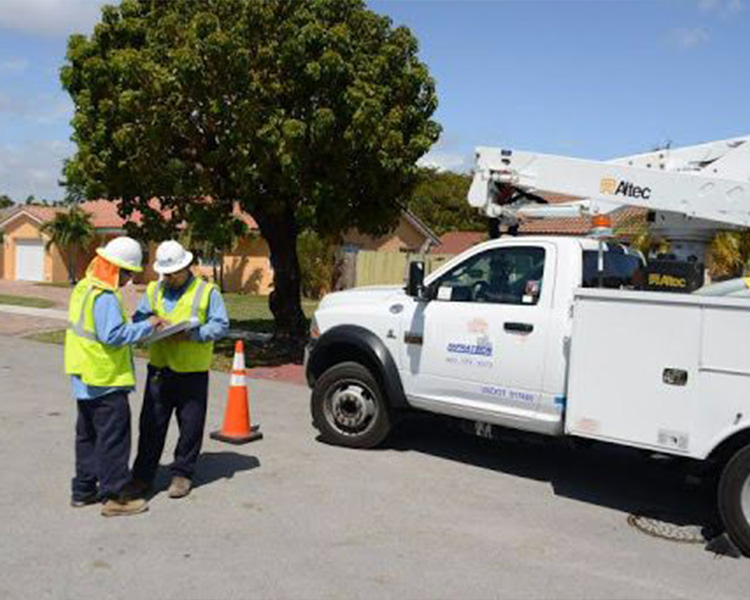 Two utility workers consult paperwork by a utility truck.