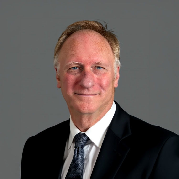 Middle-aged man in suit and tie against a gray background.