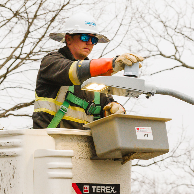 Utility worker in bucket truck fixes streetlight.