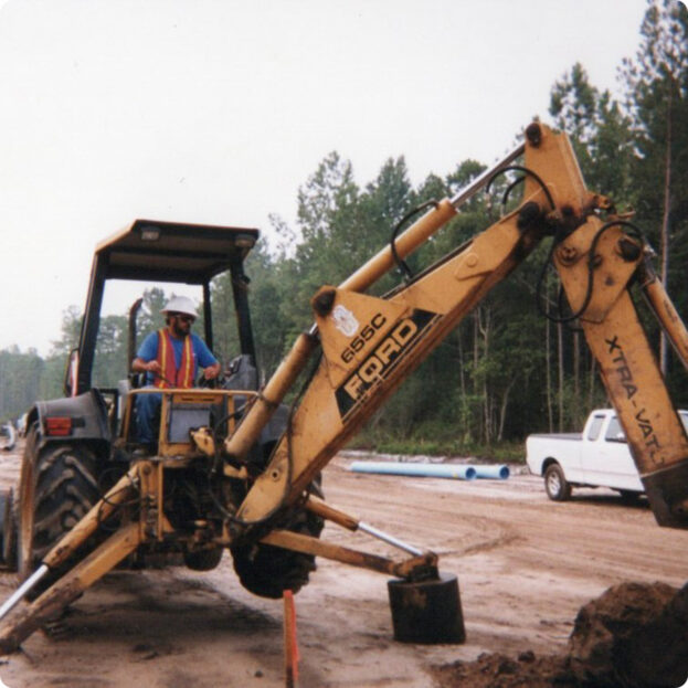 Construction worker operating an excavator on a cloudy job site.