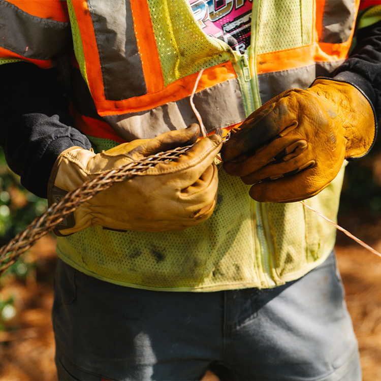 Close up of someone in safety gear wearing gloves and a yellow vest.